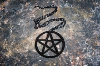 Siyah bir pentagram kolye yakın plan koyu grungy arkaplan