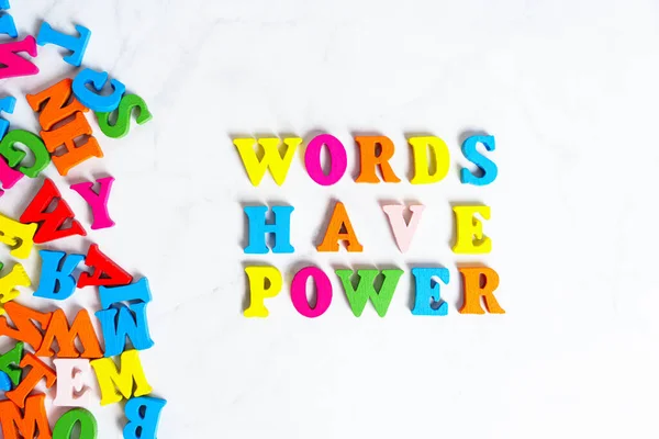 Words have power arrangement made from multicolored wooden characters on white.