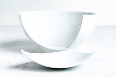 Beton zemine yerleştirilmiş kırık beyaz bir seramik kasenin yan görüntüsü.