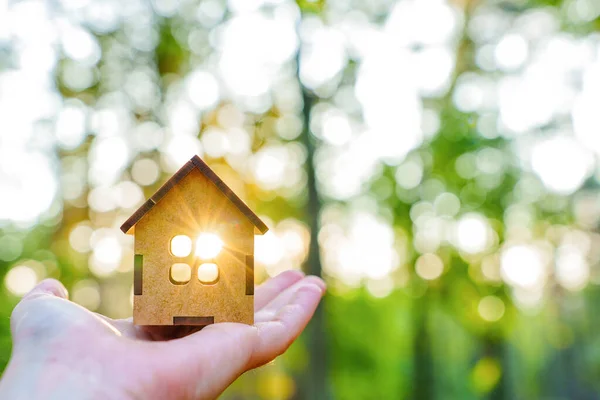 Mão Segurando Modelo Casa Madeira Iluminado Pelo Sol Contra Fundo — Fotografia de Stock