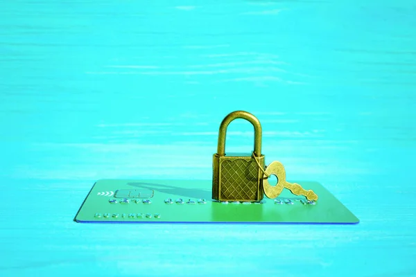 Financial fraud protection concept: credit card, padlock and master key isolated on a blue wooden background.
