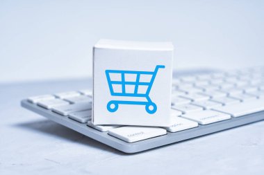 Mühürlenmiş küçük bir nakliye kutusu ve yeni bir klavyeye yerleştirilmiş bir alışveriş arabası..