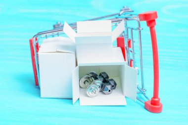 Küçük bir nakliye kutusuna konmuş küçük çelik halterler mavi ahşap arka planda izole edilmiş bir oyuncak yük vagonuna yerleştirilmiş. Beden eğitimi ekipmanları online.