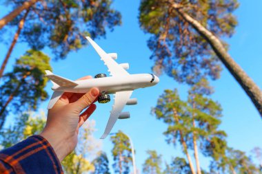 Beyaz oyuncak uçak elinde ağaçlara ve gökyüzüne karşı. Uçak modelleme kavramı.