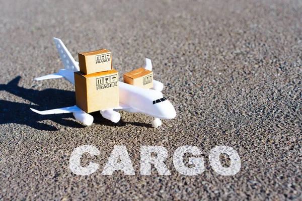 Word Cargo小さな輸送箱を運ぶおもちゃの航空機の前の滑走路に書かれた — ストック写真