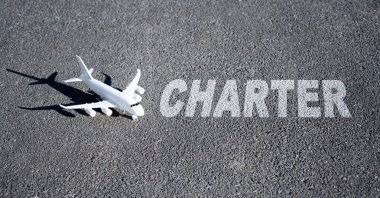 Oyuncak uçak ve kelime CHARTER gri üzerine yazılmış. Yaratıcı charter uçuş kavramı.