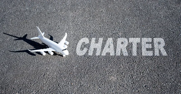 Oyuncak uçak ve kelime CHARTER gri üzerine yazılmış. Yaratıcı charter uçuş kavramı.
