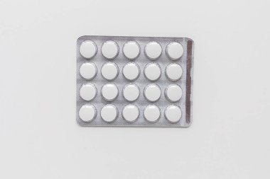 Yuvarlak beyaz haplardan oluşan gümüş bir paket. İzole edilmiş arka plan. Üst Manzara. Bir hastalığı tedavi etmek için ilaç..