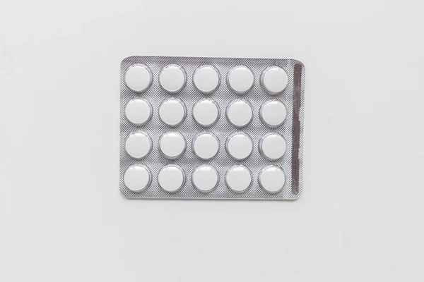 Silverblisterförpackning med runda vita tabletter. Isolerad bakgrund. Högst upp. Medicin för behandling av en sjukdom.. — Stockfoto