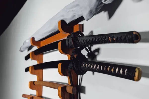 Спеціальний стенд на білій стіні для тренування мечів з дуба та заліза. Традиційна японська тренувальна зброя для різних дисциплін бойових мистецтв.. Стокове Фото
