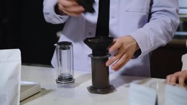 Barista fa il caffè al caffè. Versare l'acqua bollita dalla teiera in pentola aeropress con caffè macinato. — Video Stock