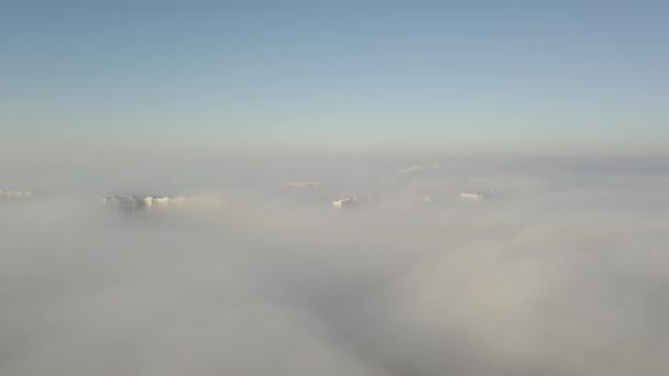 Silhouetten van hoge huizen door de binnenkomende dikke mist. Megalopolis in witte wolken in de vroege ochtend op tijd. — Stockvideo