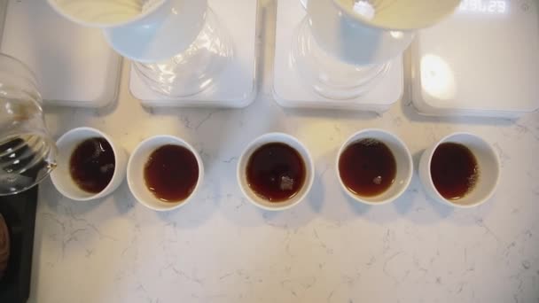 Le barista arrange et verse le café fini du filtre dans des tasses blanches. Préparation d'une boisson chaude dans un café. — Video