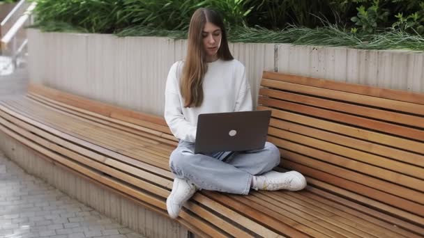 Young female in garden using laptop, communicates on internet with customer. Cozy workplace, remote work, E learning concept. Checking email, writing message in social network. — Stock Video