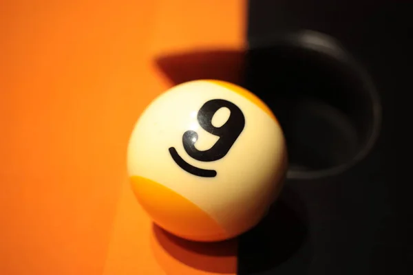 Bilardo tahtasında 9 numaralı bilardo topu bulanık arkaplanda.
