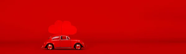 Pequeño coche rojo con dos corazones rojos. — Foto de Stock