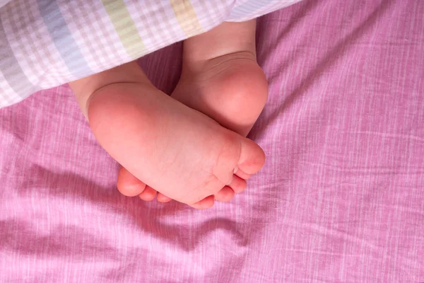 Caucásico bebé piernas desnudas en los padres cama. — Foto de Stock