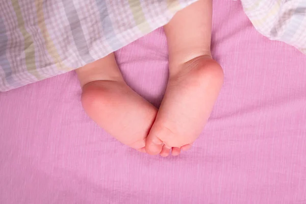 Caucásico bebé piernas desnudas en los padres cama. — Foto de Stock