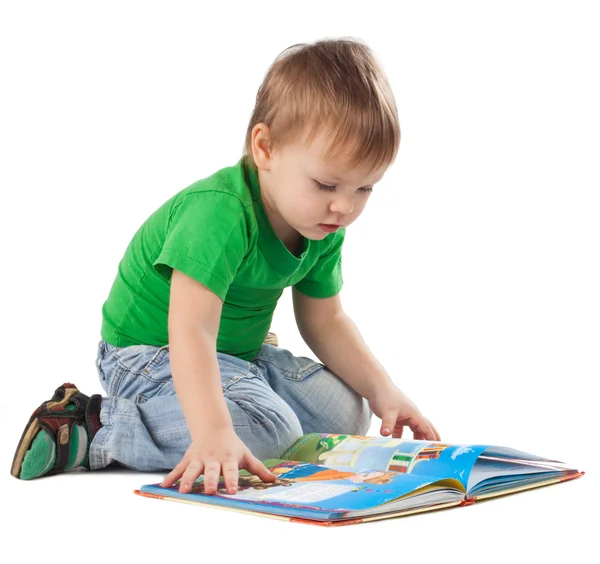 Katta oturan bir kitap olan küçük çocuk - Stok İmaj