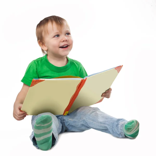 Χαμογελώντας μικρό αγόρι με ένα βιβλίο που κάθεται στο πάτωμα — Φωτογραφία Αρχείου