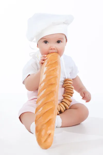 Little baker baby girl with a long loaf — Stock Photo, Image