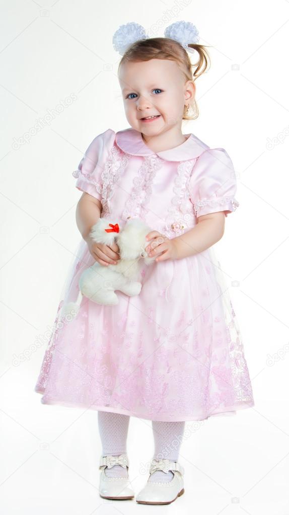 Little girl standing in full growth with toy and smiling