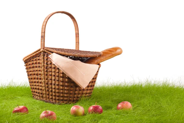 Picknickkorb mit langem Laib und Äpfeln auf dem Rasen. — Stockfoto