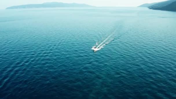 Drone vista de un barco blanco navegando en el mar azul en el fondo de las montañas. Un yate blanco moviéndose a alta velocidad. — Vídeos de Stock