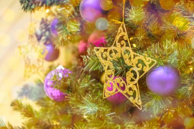 Altın yıldız ve çelenk ışıkları, arka plandaki Noel ağacındaki oyuncaklar bokeh.