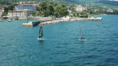 Yazın denizde rüzgar sörfü yapan iki kişi. Yelkenli sporu Eylül 2021, Lovran, Hırvatistan