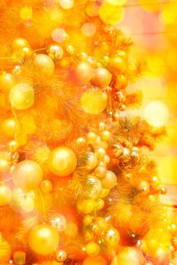 Bulanık ve parlak bir arka planda altın Noel toplarıyla süslenmiş. 