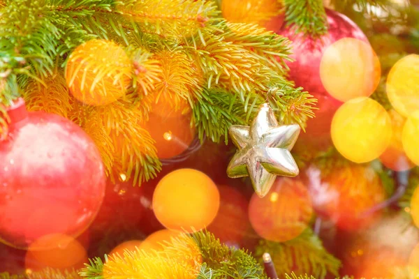 Arany csillag és koszorú fények, játékok dekoráció a karácsonyfa a háttérben fény bokeh. — Stock Fotó