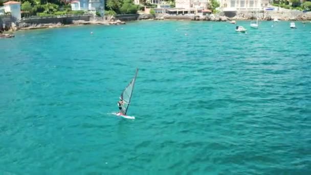 Flygbilder av drönare flyga runt person utövar vindsurfing eller segelbrädan sport i havet med turkos klart vatten — Stockvideo