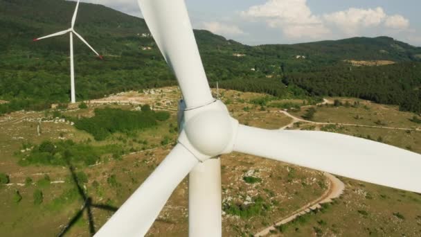 Kamera se vzdaluje od rotující větrné turbíny. Letecký pohled na větrnou farmu v horách. Výroba zelené ekologické energie a elektřiny, — Stock video