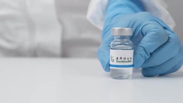CanSinoBIO injekciós üveg gyógyszerrel, melyet egészségügyi dolgozó helyezett az asztalra gumikesztyűben és PPE öltönyben, 2021. május, San Francisco, USA — Stock videók