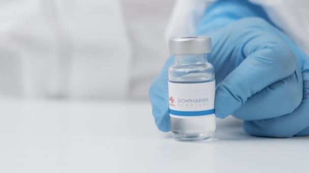 Flacon bio pharmaceutique avec médicament mis sur la table par un agent de santé en gants de caoutchouc et combinaison EPI, mai 2021, San Francisco, États-Unis — Video