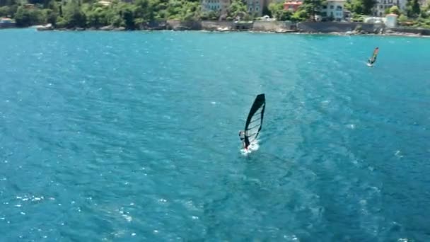 Imágenes aéreas de aviones no tripulados volando alrededor de la persona practicando windsurf o deporte de vela en el mar con agua turquesa clara — Vídeos de Stock