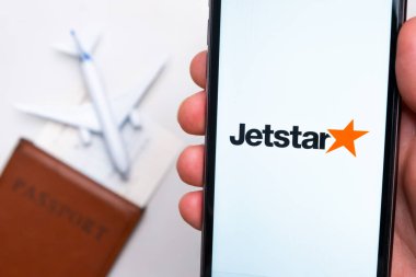 Pasaport, bilet ve uçak arka planında akıllı telefon ekranında Jetstar Havayolları logosu, Eylül 2021, San Francisco, ABD