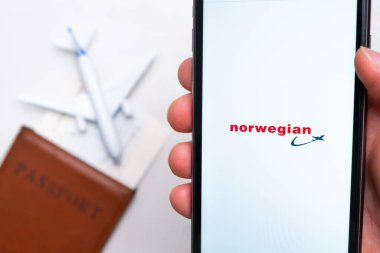 Pasaport, bilet ve uçak arka planında akıllı telefon ekranında Norveç havayolları logosu, Eylül 2021, San Francisco, ABD