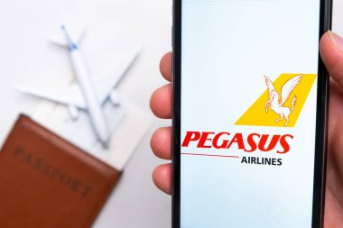 Pasaport, bilet ve uçak arka planında akıllı telefon ekranında Pegasus Havayolları logosu, Eylül 2021, San Francisco, ABD