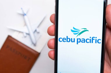Pasaport, bilet ve uçak arka planında akıllı telefon ekranında Cebu Pacific Havayolları logosu, Eylül 2021, San Francisco, ABD