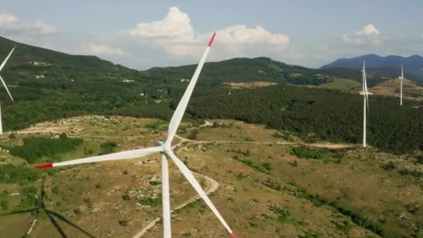 La cámara gira alrededor de un aerogenerador girando en las montañas. Vista aérea de un parque eólico en verano. Generación de electricidad verde y renovable. — Vídeos de Stock