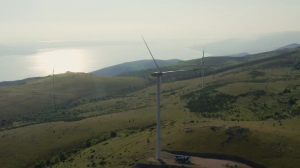 Аэросъемка ветряных турбин в горах на фоне острова Крк в Хорватии. Производство зеленой электрической энергии — стоковое видео