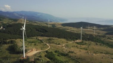 Rüzgâr türbinlerinin üzerinde dönen bir dronun dağlardaki hava görüntüleri. Rüzgar değirmenleri iklim değişikliklerini önlemek için yeşil enerji üretir.
