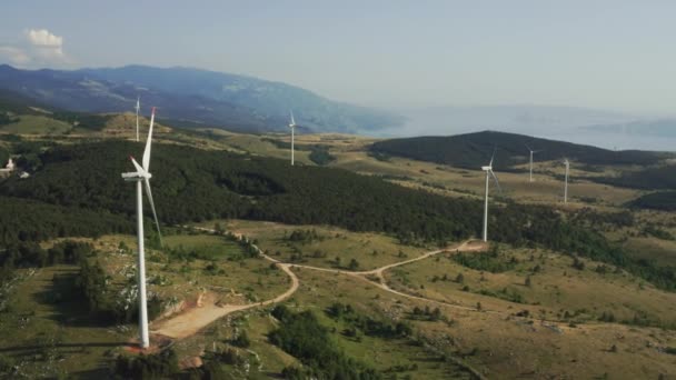 Aerial footage of a drone rotating over spinning wind turbines highly in the mountains. Wind mills generate green power to avoid climate changes — Stock Video