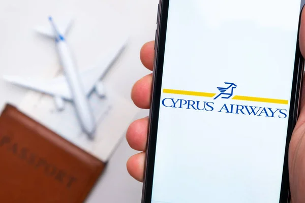 Vías aéreas de Chipre. Un teléfono móvil y la aplicación de las vías respiratorias de Chipre en manos de los hombres. Hay un pasaporte y un avión en una mesa blanca. Noviembre 2021, San Francisco, EE.UU.. — Foto de Stock