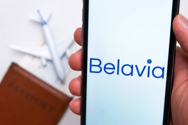 Belavia Havayolları uygulaması cep telefonu ekranında arka planda uçak, uçuş kartı ve pasaportlu adamlar var. Havayolları mobil uygulaması kavramı. Kasım 2021, San Francisco, ABD.