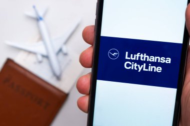Lufthansa CityLine Havayolları. Bir cep telefonu ve Lufthansa CityLine havayolu uygulaması. Beyaz bir masada bir pasaport ve bir uçak var. Kasım 2021, San Francisco, ABD.