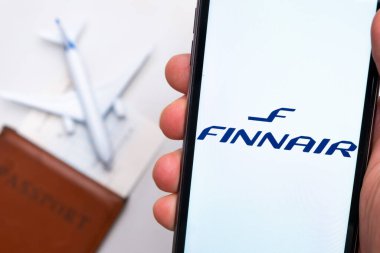 Finnair Havayolları. Bir cep telefonu ve Finnair Havayolları uygulaması. Beyaz bir masada bir pasaport ve bir uçak var. Kasım 2021, San Francisco, ABD.