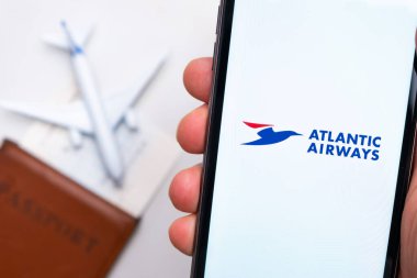 Atlantic Havayolları. Bir cep telefonu ve Atlantic Airways havayolları uygulaması. Beyaz bir masada bir pasaport ve bir uçak var. Kasım 2021, San Francisco, ABD.